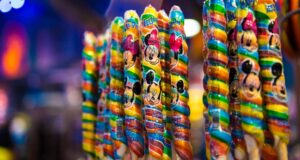 Vibrant swirled lollipops with Disney character wrappers line the shelves, a nostalgic treat for guests at Walt Disney World.