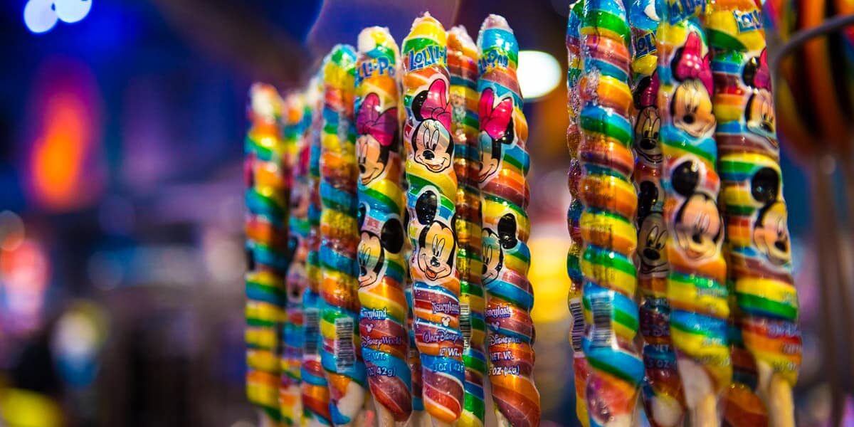 Vibrant swirled lollipops with Disney character wrappers line the shelves, a nostalgic treat for guests at Walt Disney World.