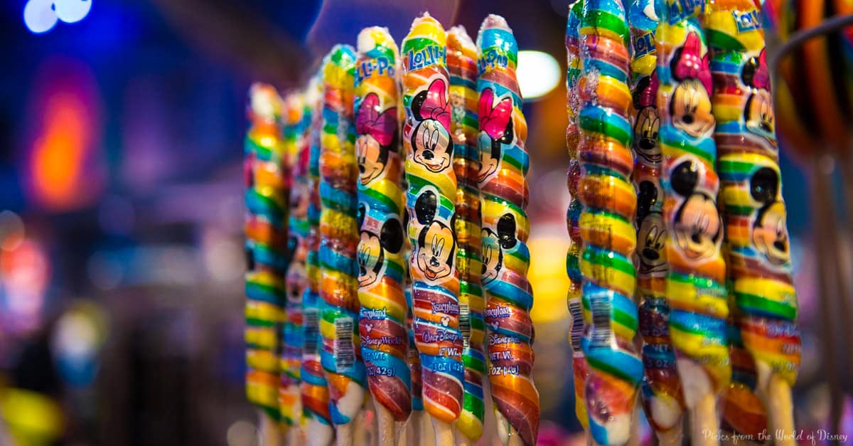Vibrant swirled lollipops with Disney character wrappers line the shelves, a nostalgic treat for guests at Walt Disney World.