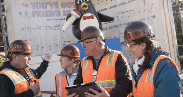 Construction crew chats in front of Wheezy and a "You've Got a Friend" sign at Toy Story Land in Walt Disney World.