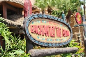 The vibrant Enchanted Tiki Room sign pops amid lush tropical foliage, welcoming Disney World guests to this iconic attraction.