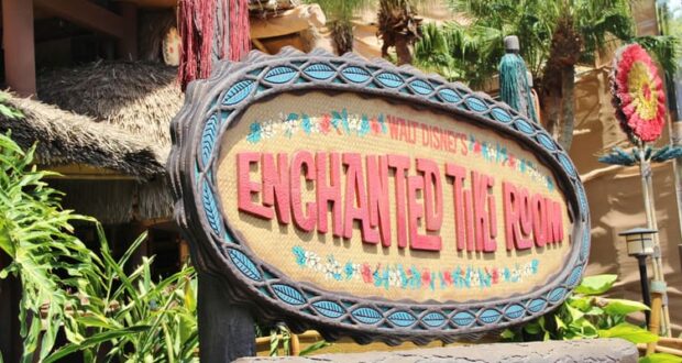 The vibrant Enchanted Tiki Room sign pops amid lush tropical foliage, welcoming Disney World guests to this iconic attraction.