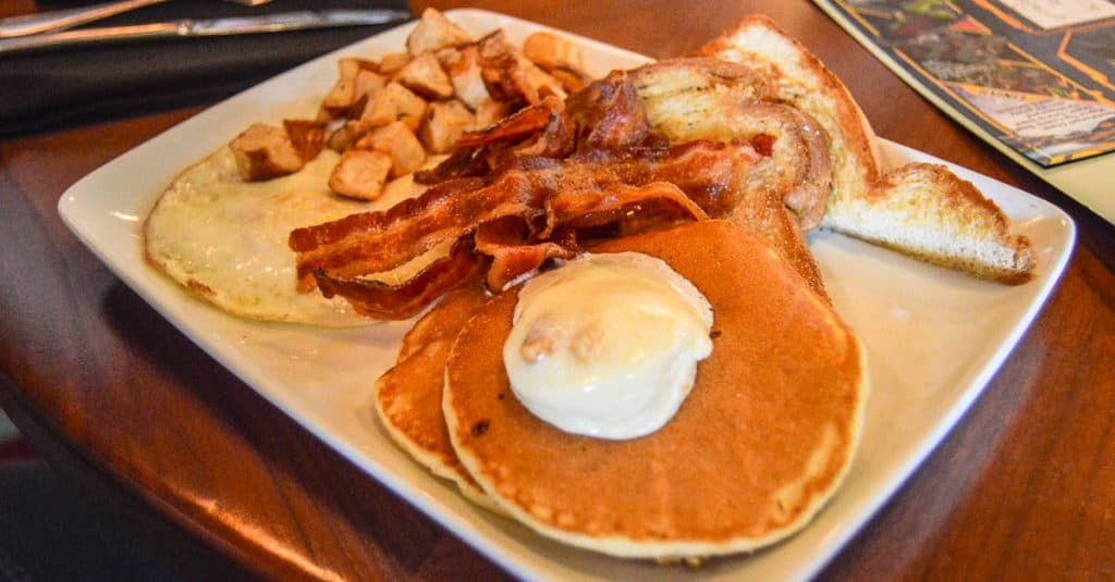 Fuel up for adventure at Walt Disney World with pancakes, bacon, eggs, toast, and home fries on a white square plate.