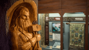 Thor statue, intricately carved in wood with his hammer, stands before an immersive Norse mythology display at the attraction.
