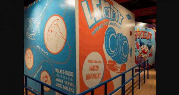 Toy Story Mania’s vibrant, cartoon-style walls pop with playful graphics of Chuckles and Lenny, framed by bright blue railings.