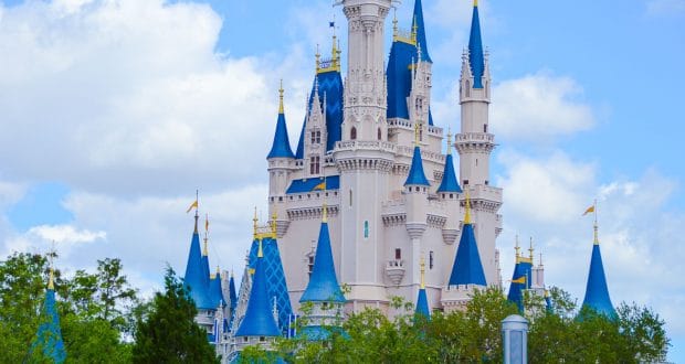 Cinderella Castle’s blue and white spires rise above lush trees under a clear sky—Walt Disney World’s iconic fairytale landmark.