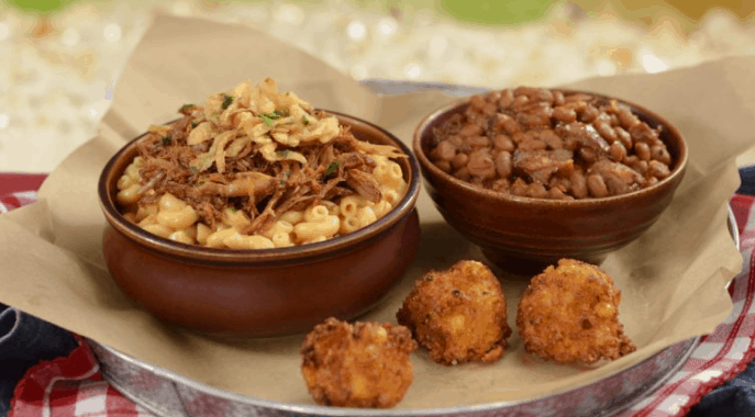 Indulge in Diamond Horseshoe’s mac and cheese, loaded with pulled pork, baked beans, and crispy fried cheese balls at Disney World.