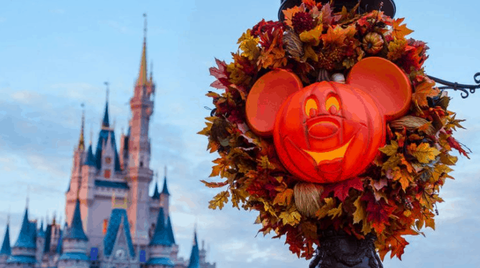 Mickey Mouse pumpkin and autumn leaves in front of Cinderella Castle celebrate the festive Disney Fall Into Magic at Walt Disney World.