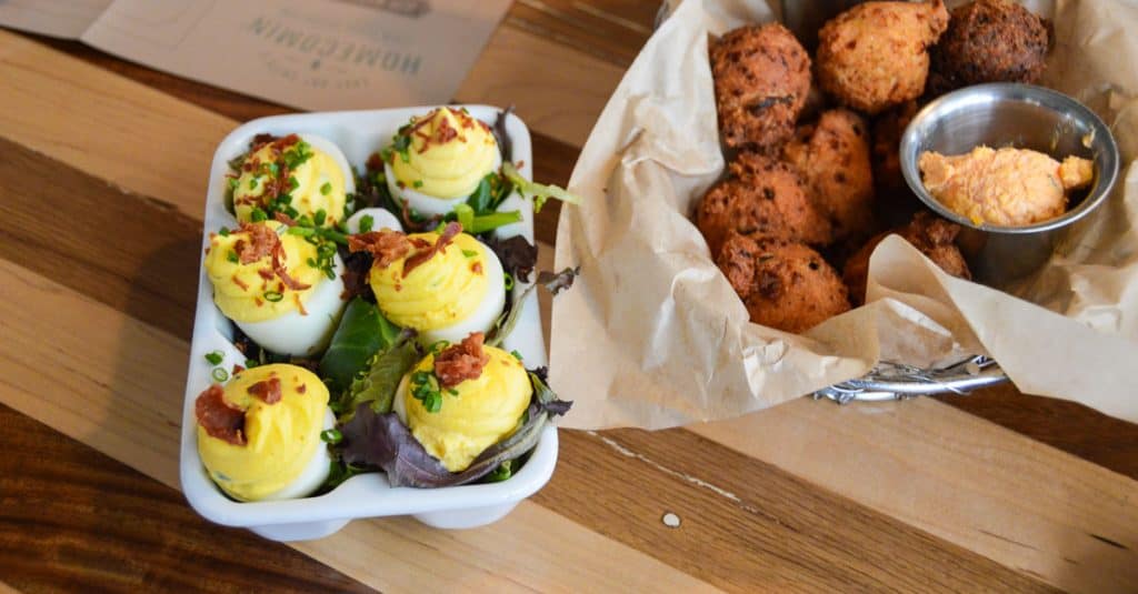 Deviled eggs with bacon and chives plus hush puppies and dip—fan-favorite Southern snacks at Chef Art Smith’s Homecoming, Disney Springs.