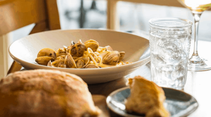 Classic Italian fare at Terralina Crafted Italian in Disney Springs—a bowl of clams pasta, crusty bread, water, and wine.