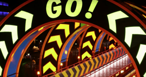 Neon "GO!" sign with yellow arrows lights up the Toy Story Land tunnel at night, energizing guests with signature Pixar flair.