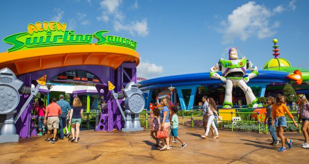 Guests stroll past the Alien Swirling Saucers attraction and Buzz Lightyear statue in Toy Story Land at Disney’s Hollywood Studios.