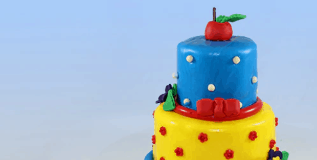Disney-inspired two-tier cake with blue and yellow icing, red accents, and a red apple topper—Wilderness Lodge celebration-ready.