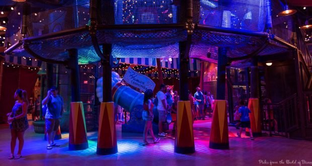 Guests immerse themselves in a vibrant play zone at Disney World, surrounded by nets, cones, and dazzling blue-purple lights.