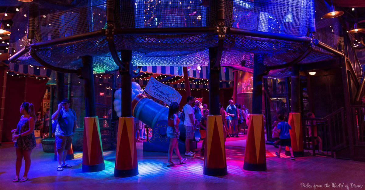 Guests immerse themselves in a vibrant play zone at Disney World, surrounded by nets, cones, and dazzling blue-purple lights.
