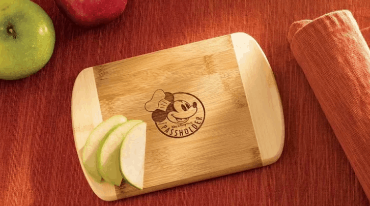 Mickey Mouse Passholder cutting board beside sliced green apple and red napkin—an epicurean must for Disney World fans.