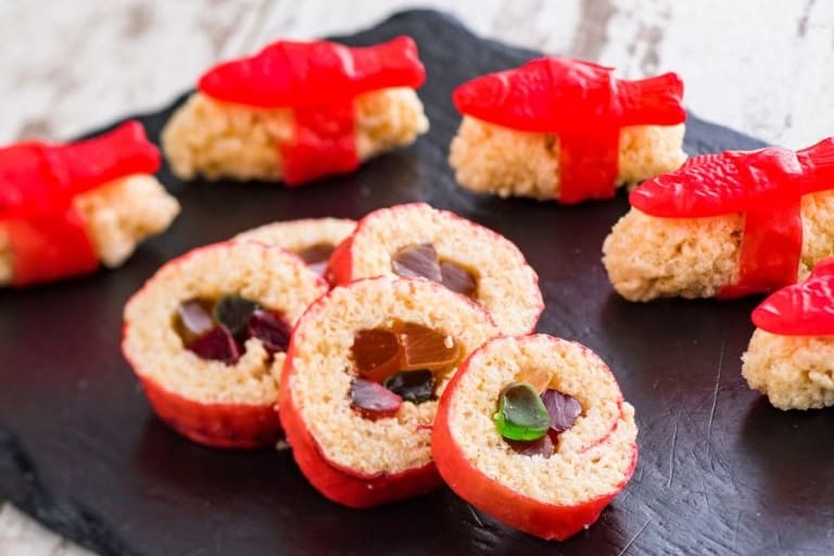 Sushi-inspired Rice Krispies treats with gummy fish and candies, just like at Epcot Food & Wine Festival, on a slate tray.