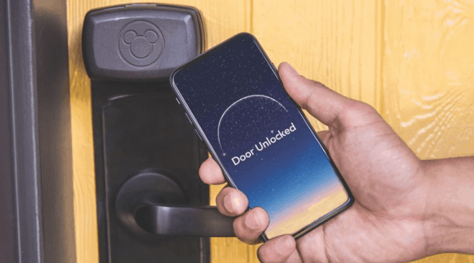 Unlocking magic at Disney Resorts: a phone with "Door Unlocked" held by a Mickey lock, highlighting the Digital Key feature.