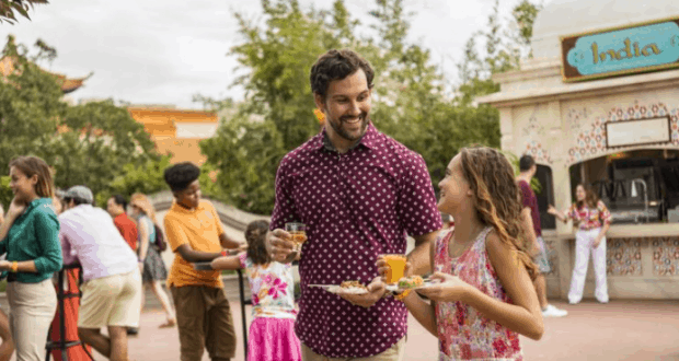 Guests savor delicious bites and drinks at EPCOT’s Food & Wine Festival, smiling amid the festive crowds and vibrant park energy.