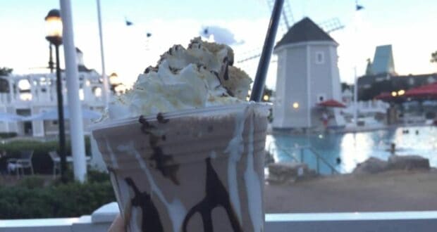Decadent milkshake topped with whipped cream and chocolate drizzle enjoyed poolside during the Crescent Lake Adult Beverage Crawl at Walt Disney World, with the iconic BoardWalk windmills in the background.