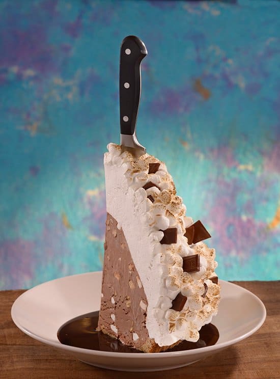 Indulge in a giant ice cream pie slice topped with whipped cream and chocolate at Disney Springs, knife dramatically on top.