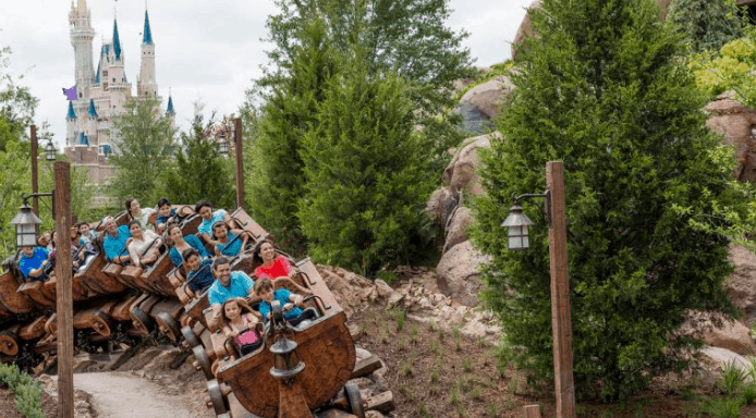 Guests soar on a thrilling coaster past lush woods with Cinderella Castle in view, experiencing Early Morning Magic at Disney World.