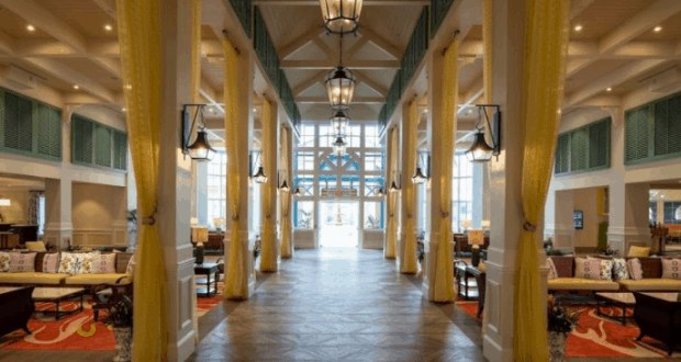 Caribbean Beach Resort lobby near Disney World, featuring high ceilings, yellow drapes, cozy seating, and sunlit windows.