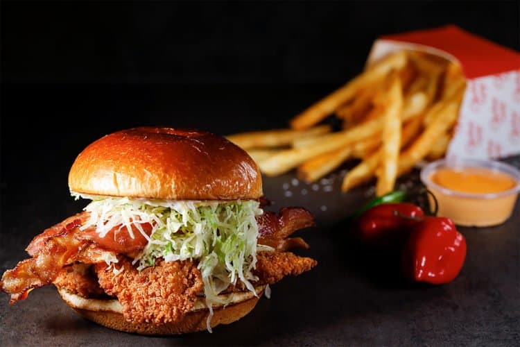 A Chicken Guy-style sandwich with lettuce and bacon, fries, dip, and peppers—just like you’d find at Walt Disney World.