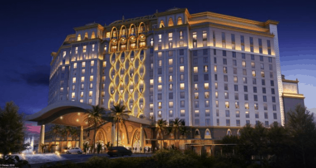 The illuminated 15-story Gran Destino Tower glows at night amid palm trees at Disney’s Coronado Springs Resort.