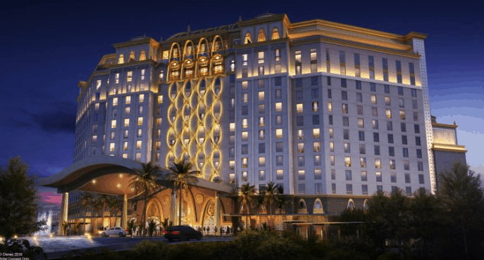 The illuminated 15-story Gran Destino Tower glows at night amid palm trees at Disney’s Coronado Springs Resort.