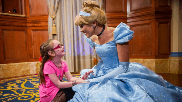 A young guest beams while holding hands with Cinderella in her signature blue gown, creating magical moments at Walt Disney World.