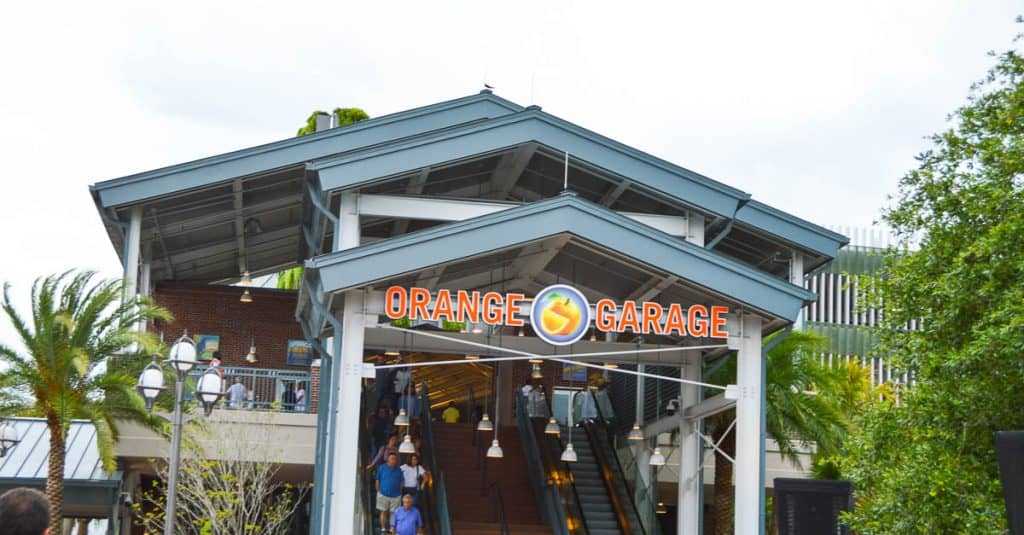 Orange Garage entrance at Disney Springs with bold signage and escalators, framed by trees—your gateway to a Disney World adventure.
