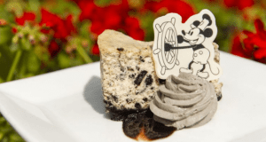 Cookies and cream cheesecake topped with grey whipped cream and a Mickey Mouse decoration, served at Walt Disney World.