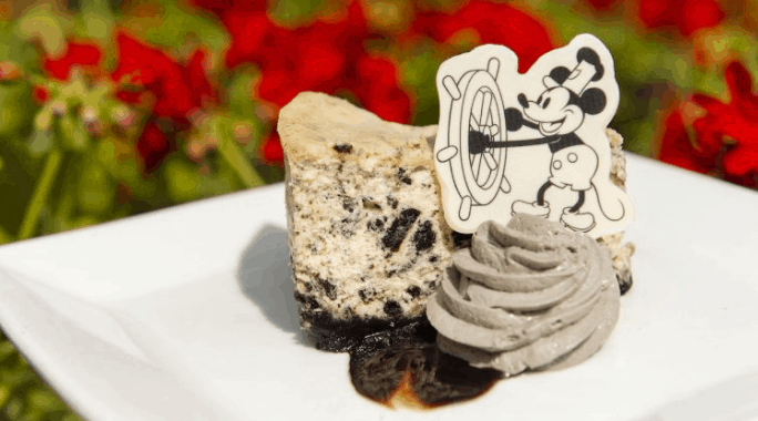 Cookies and cream cheesecake topped with grey whipped cream and a Mickey Mouse decoration, served at Walt Disney World.