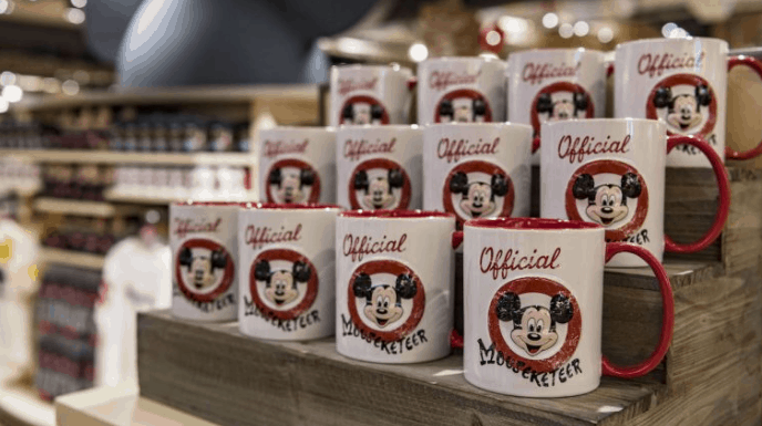 Official Mouseketeer mugs with Mickey Mouse are lined up on Disney Springs shelves, ready for magical birthday celebrations.