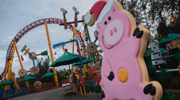 Hamm in a Santa hat greets guests in front of a vibrant ride, bringing festive cheer to Toy Story Land at Disney World.