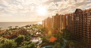 Aulani Resort and Spa, Disney’s Hawaiian escape, features soaring towers, tropical gardens, and a pool glowing at sunset.