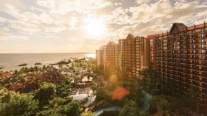 Aulani Resort and Spa, Disney’s Hawaiian escape, features soaring towers, tropical gardens, and a pool glowing at sunset.