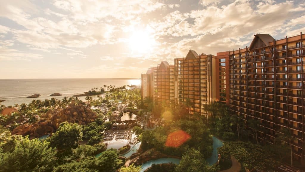 Aulani Resort and Spa, Disney’s Hawaiian escape, features soaring towers, tropical gardens, and a pool glowing at sunset.