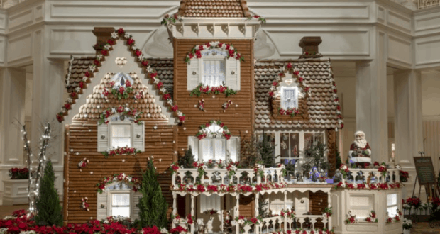 Stunning Gingerbread House decked with festive garlands, lights, and flowers at Walt Disney World’s holiday celebration indoors.