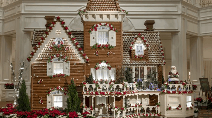 Stunning Gingerbread House decked with festive garlands, lights, and flowers at Walt Disney World’s holiday celebration indoors.