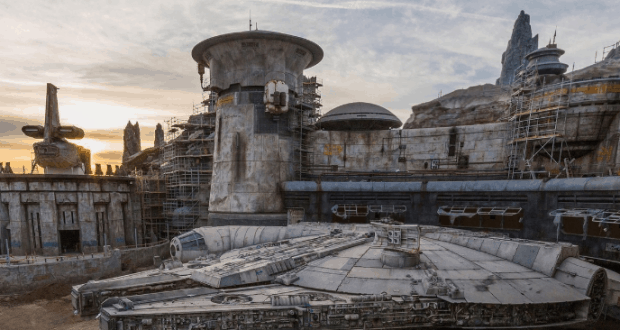 The Millennium Falcon docked at Star Wars: Galaxy’s Edge, surrounded by Batuu’s sci-fi architecture at sunset in Disney World.