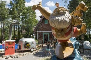 Santa Claus in swim trunks greets guests by a festive house and trailer, with snowy fun at Winter Summerland Miniature Golf.