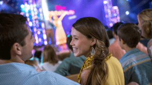 Guests seated at Epcot’s Festival of the Arts watch Disney on Broadway’s vibrant stage show, dazzled by colorful lights.