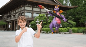 A boy points excitedly at Figment, the purple dragon, wielding a giant paintbrush near Epcot's temple during Festival of the Arts.