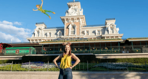 A guest beams at the Magic Kingdom entrance as Peter Pan flies overhead in a whimsical Disney PhotoPass Magic Shot experience.