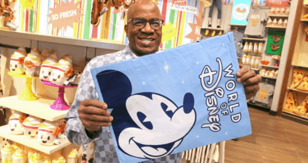 A guest shows off a blue World of Disney Mickey Mouse flag inside a vibrant Disney World shop stocked with reusable bags.
