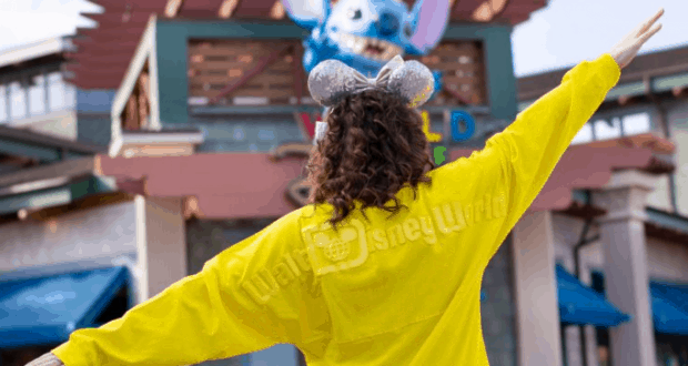 Disney World guest in yellow park shirt and sparkling Mickey ears greets the entrance, ready for an unforgettable weekend adventure.