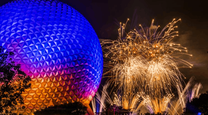 Spaceship Earth glows after dark as IllumiNations fireworks dazzle nearby, creating a classic Epcot nighttime spectacle.