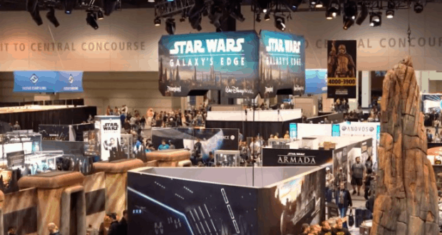 Galaxy’s Edge banners and Walt Disney World displays fill the lively Star Wars convention hall, lined with themed booths and props.